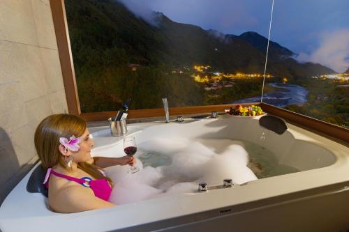 a woman sitting in a bath tub with a glass of wine at Aldea Real Eco Friendly in Baños