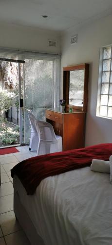 a bedroom with a bed and a desk and chairs at Lytton Cresent B&B in Pinetown