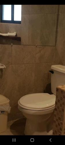 a bathroom with a white toilet and a window at Hotel la Cueva Limon in Puerto Limón