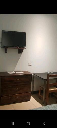 a desk with a television on a wall with a chair at Hotel la Cueva Limon in Puerto Limón