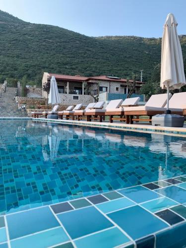 a large swimming pool with chairs and umbrellas at Kairos Hotel in Kas
