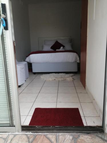 a bedroom with a bed and a red rug at Lytton Cresent B&B in Pinetown