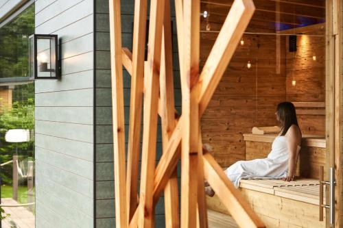 a woman sitting in a sauna at Hotel Erasmus - Mein Genuss- und Wellnesshotel in Trassem