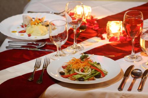 a table with two plates of food and wine glasses at Villa Kayu Raja in Seminyak
