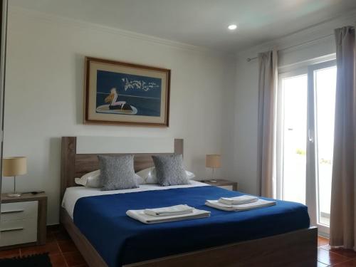 a bedroom with a blue bed with towels on it at PoolSeaView Spacious House in Atouguia da Baleia