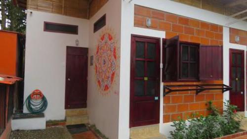 una casa con puertas rojas y una pared de ladrillo en Esperanto Bed & Breakfast Surf Hostel en Montañita