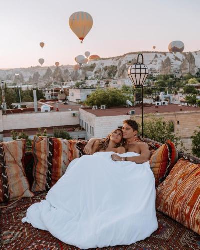 a bride and groom sitting on a couch with hot air balloons at Cappadocia Caves Hotel in Goreme