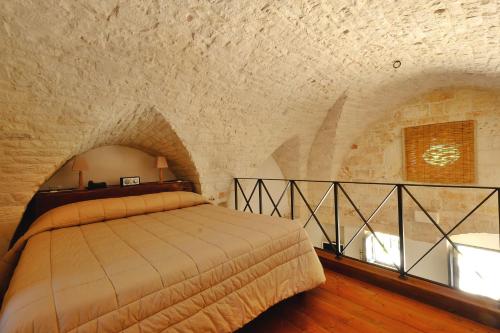 a bedroom with a bed in a stone wall at Masseria Trulli e Vigne in Martina Franca