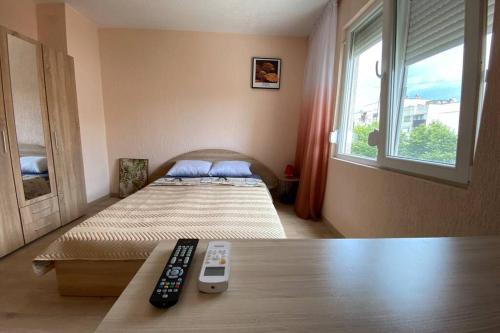 1 dormitorio con 1 cama con 2 mandos a distancia en Sunny apartment by the river, en Sandanski