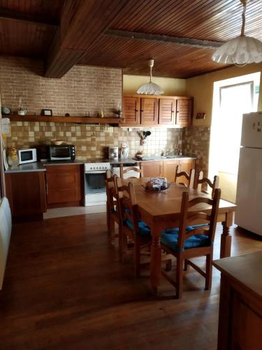 une cuisine avec une table en bois avec des chaises et un réfrigérateur dans l'établissement Maison familiale centenaire de vigneron, à Montescot