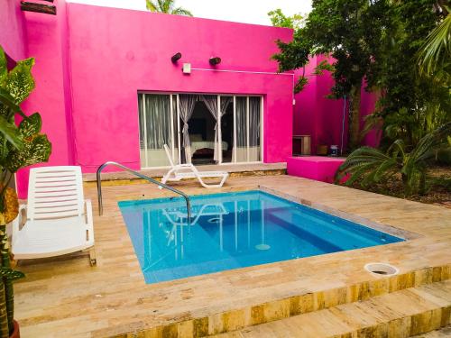 una casa rosa con piscina frente a ella en Casa Isabella, en Cozumel
