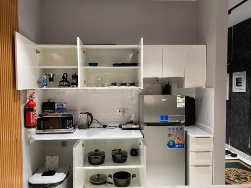 eine kleine Küche mit weißen Schränken und einem Kühlschrank in der Unterkunft Maqeela Luxury Studio in King Abdullah Economic City