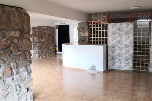 Habitación grande con pared de piedra y mesa blanca. en Susan Home, en San Martín de Valdeiglesias