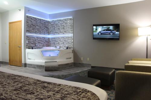 Habitación de hotel con bañera y TV en Westbridge Inn & Suites, en Carrollton
