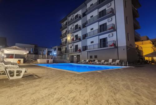 a swimming pool in front of a building at night at Kharisma Hotel in Mamaia Nord