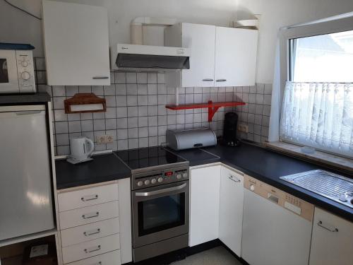 a kitchen with white cabinets and a stove top oven at Haus Fuchskaute Monteurzimmer in Willingen