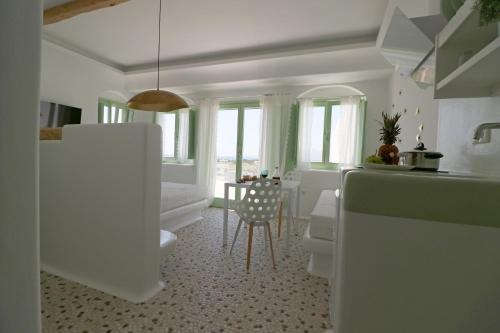 a white kitchen with a table and a chair at Vino suites in Agia Anna Naxos