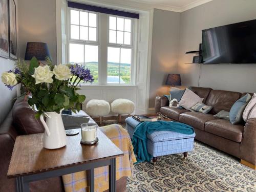 uma sala de estar com um sofá e uma mesa com flores em Arran School House - Blackwaterfoot, Isle of Arran em Blackwaterfoot