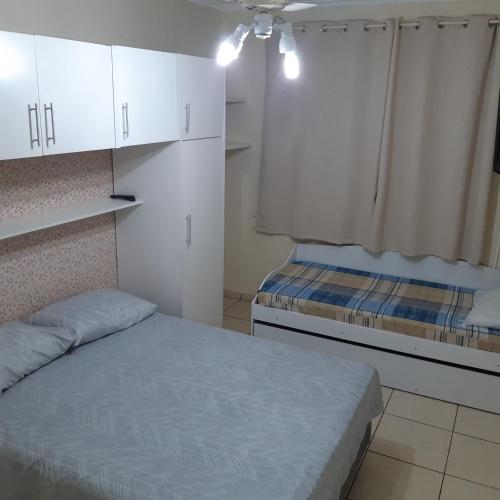 Dormitorio pequeño con cama y armarios blancos en Apartamento Guaruja Enseada 2 Quadra da Praia Atrás do Aquario en Guarujá