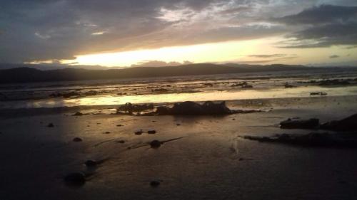 a sunset on a beach with the tide coming in at Roneragh Apartments Paul's place The Only Penthouse Apartment in Fahan