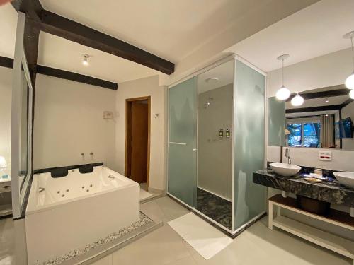 a bathroom with a tub and a shower and a sink at Porto Pacuíba Hotel in Ilhabela
