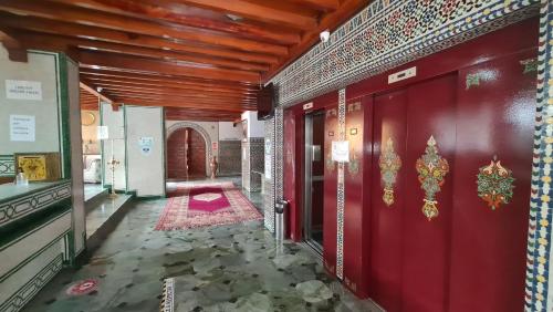 Hotel Le Grand Imilchil في مراكش: ممر به جدران حمراء وباب احمر