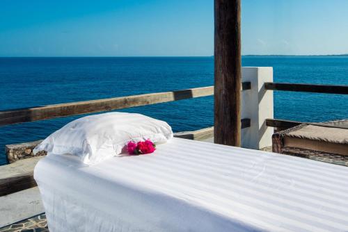 a white bed with flowers on top of the ocean at Samsara Cliff Resort in Negril