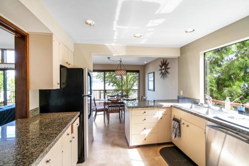 a kitchen with white cabinets and a large window at PNW MCM 155ft Private Waterfront Gem on Raft Island with Hot Tub in Gig Harbor