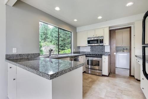 a kitchen with white appliances and a large window at PNW MCM 155ft Private Waterfront Gem on Raft Island with Hot Tub in Gig Harbor