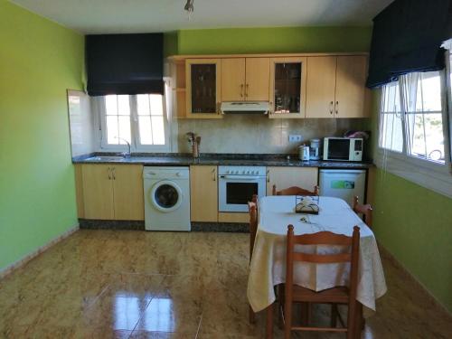 a kitchen with a table and a kitchen with green walls at Apartamentos Turísticos San Breixo in Carballo