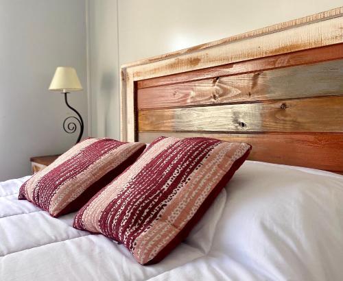 a bed with a wooden headboard and two pillows on it at Casita de Piedra 2 in Trinidad