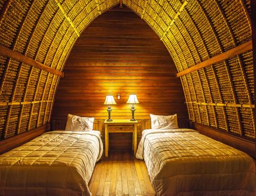 a bedroom with two beds and a table with two lamps at Sukanusa Luxury Huts in Nusa Lembongan