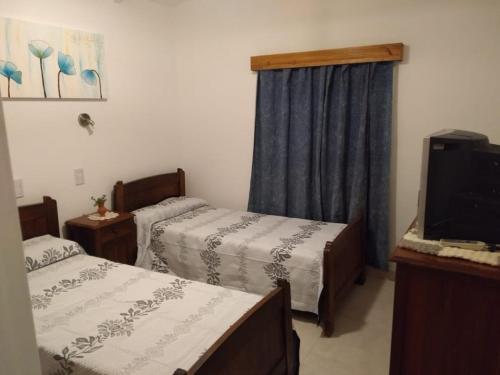 um quarto de hotel com duas camas e uma televisão em Casa El Descanso em La Cumbre