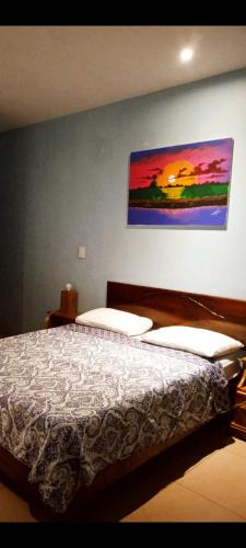 a bedroom with a bed with a painting on the wall at Hotel la Cueva Limon in Puerto Limón