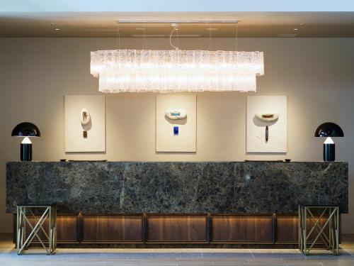 a lobby with a black counter and a chandelier at MB GALLERY CHATAN by THE TERRACE HOTELS in Chatan
