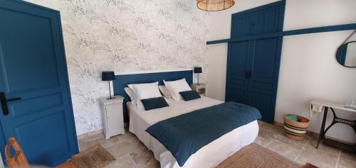 una camera da letto con porte blu e un letto con cuscini di MAS DE LA FADETO a Les Baux-de-Provence