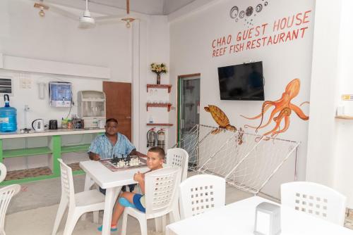 a man and a boy sitting at a table in a restaurant at Chao Guest House in Maafushi