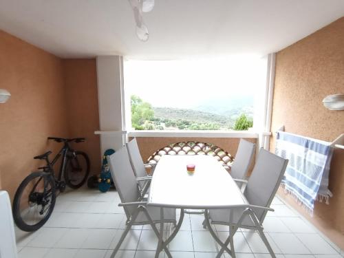 una mesa blanca y sillas en un balcón con una bicicleta en Cap Esterel studio H3, en Agay - Saint Raphael