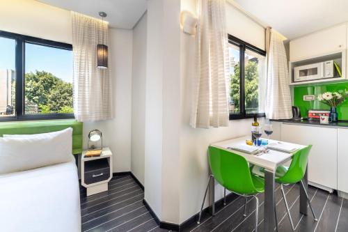 a room with a bed and a table with green chairs at 130 Rock Apartments in Tel Aviv
