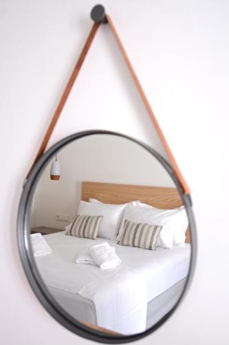 a mirror reflecting a bed with white sheets and pillows at Pénde Suites in Livadion