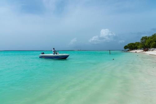 a man on a boat in the water on a beach at Chao Guest House in Maafushi