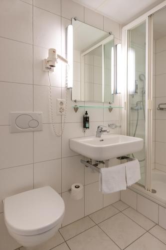 a white bathroom with a toilet and a sink at Landgasthof Kreuz - Der Zwischenstopp mit Herz auf dem Weg in den Süden in Kappel bei Olten