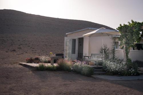 a small house with an umbrella and a bench at פטריוט -יקב ננה in Mitzpe Ramon