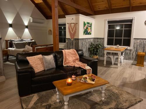 a living room with a black leather couch and a table at Trawool Shed Cottages, Cafe and Restaurant in Seymour