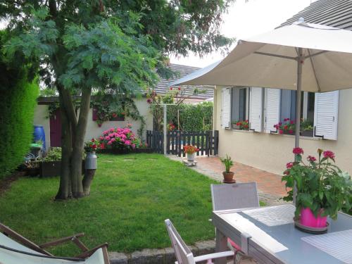 einen Tisch mit einem Regenschirm im Hof in der Unterkunft chez Annick in La Flèche