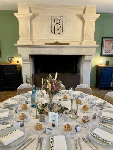 a table with white plates and a fireplace at Logis Hotel Le Blason de Provence in Monteux