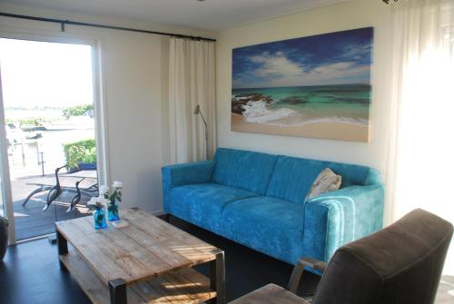 a living room with a blue couch and a coffee table at Chalet Veluwemeerzicht Elburg in Biddinghuizen
