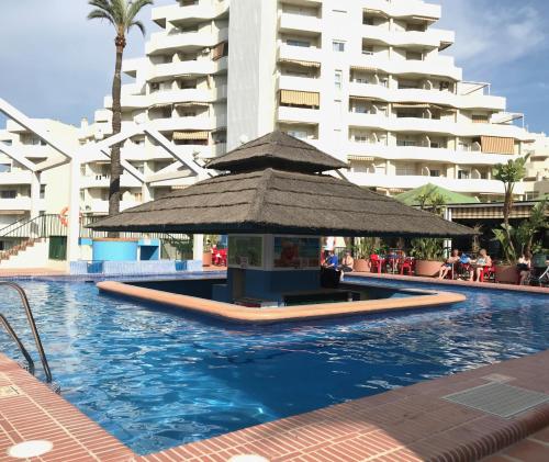 ein Swimmingpool mit einem Sonnenschirm in der Mitte eines Gebäudes in der Unterkunft Benal Beach Sea View Apartment (Benalmadena) in Benalmádena