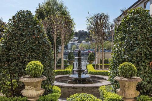 a fountain in a garden with two bushes at Perryville House in Kinsale