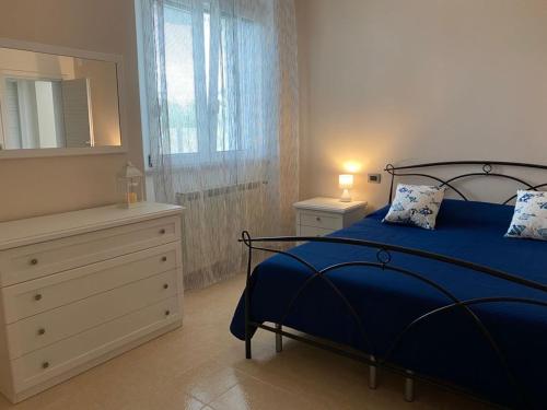 a bedroom with a blue bed with a dresser and a mirror at Villa Baccile in Fossacesia